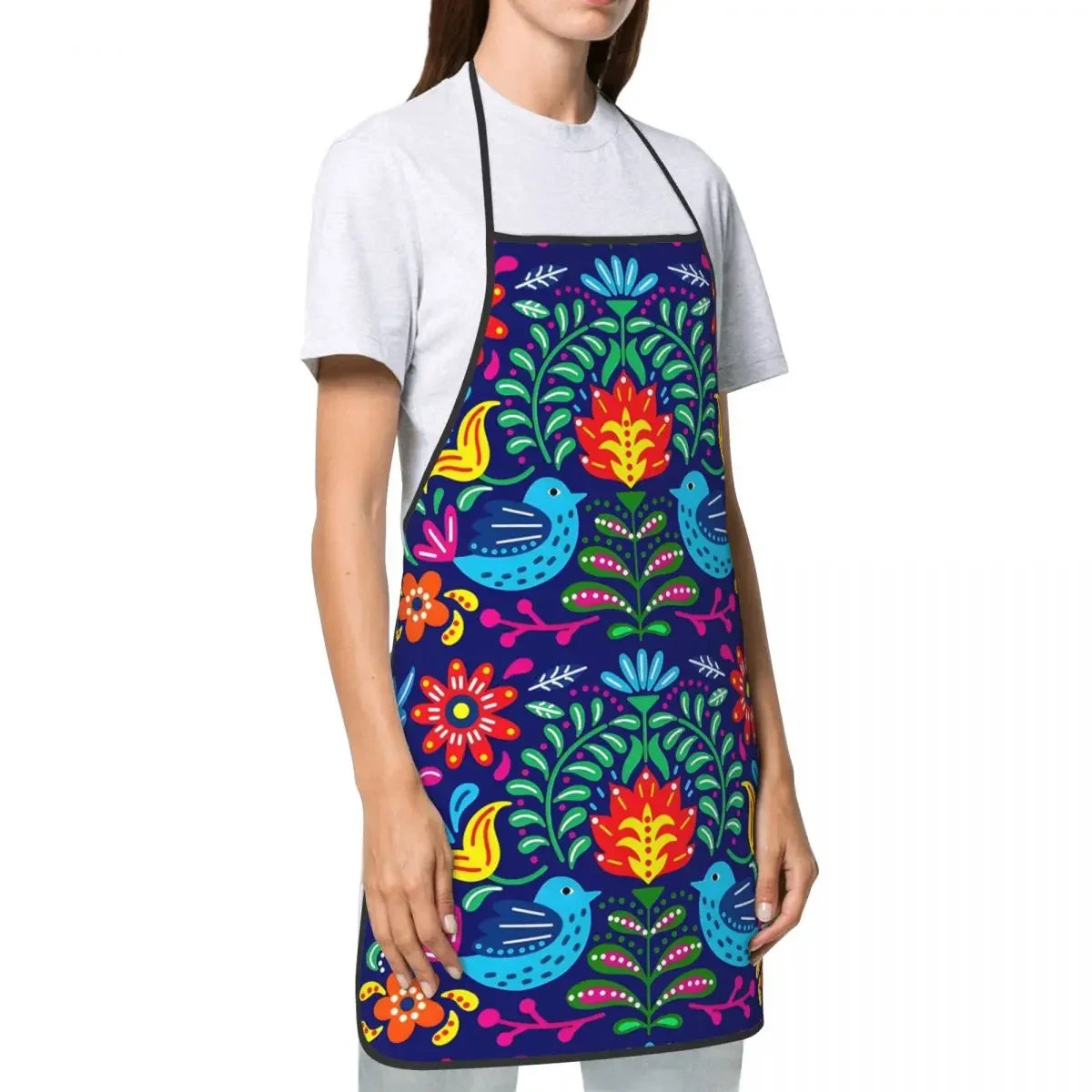 A woman wearing a dark blue floral art apron over a white t-shirt.