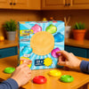 Hands are interacting with a box of 4 types of dumpling squishy stress relief toys on a wooden table.