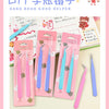A set of pink and blue macaron color craft tweezers for scrapbooking and journaling displayed in a box.