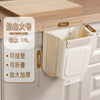 A beige foldable hanging trash bin with a lid is shown on a wooden countertop.