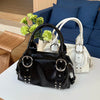 A black soft PU leather shoulder bag with silver rivet accents resting on a white table.
