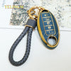 A gold-colored key fob with a dark blue cover and a braided cord attached, featuring multiple buttons.
