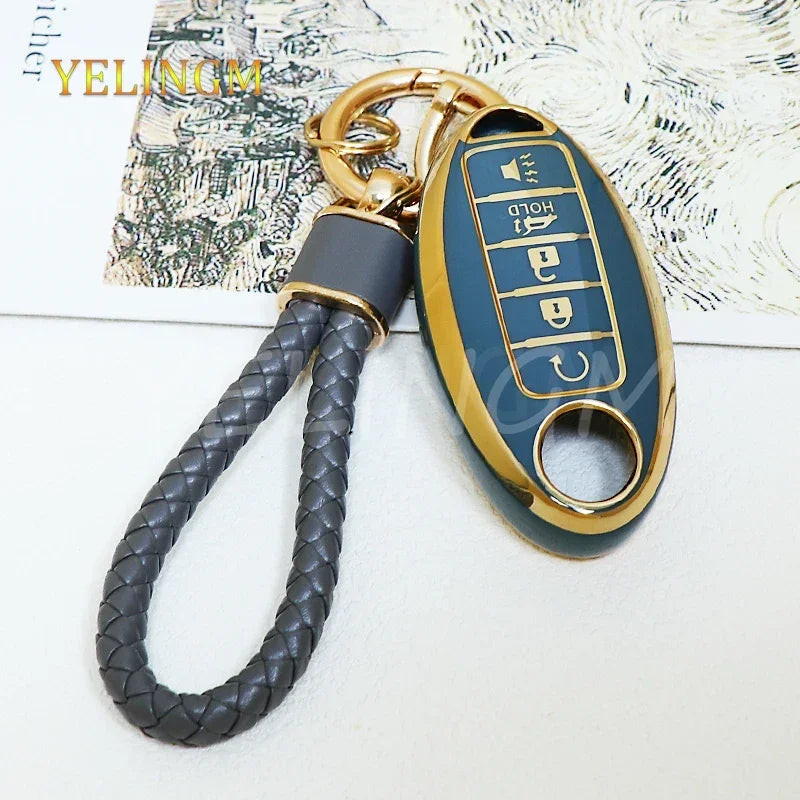 A gold-colored key fob with a dark blue cover and a braided cord attached, featuring multiple buttons.