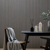 A dark wood table set against a gray vertical slat wall with candles and a draped cloth.