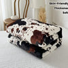 A stack of brown and black cow print flannel blankets resting on a white surface.