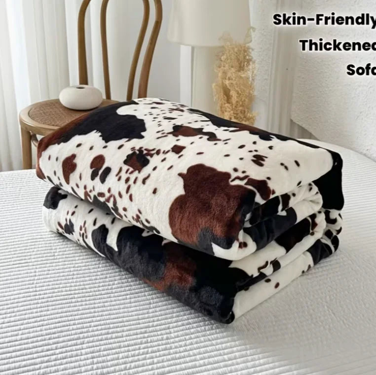 A stack of brown and black cow print flannel blankets resting on a white surface.