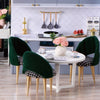 A white dining table set with green velvet chairs and a wooden dollhouse miniature building kit.