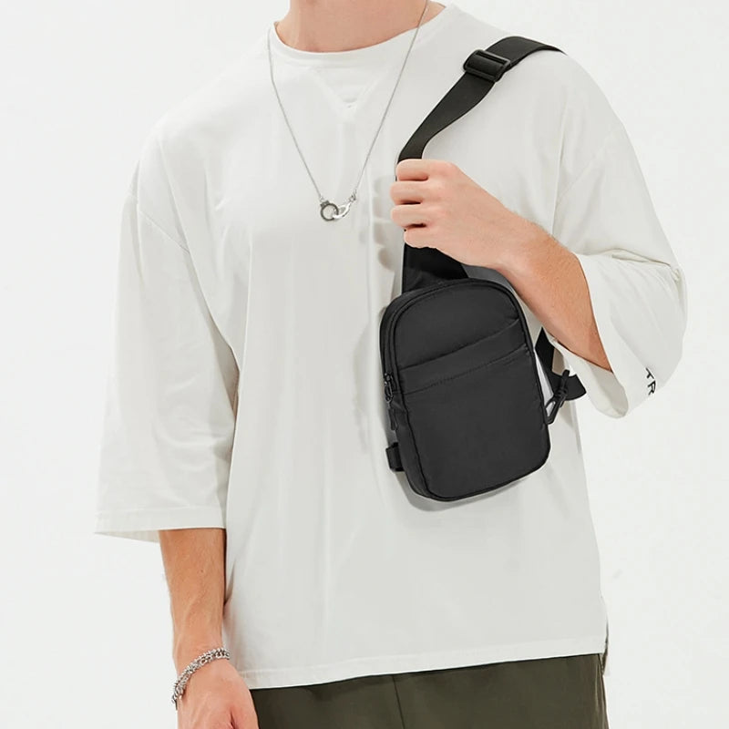 A person wearing a white t-shirt is holding a black 2-in-1 convertible waist and crossbody sling bag.
