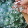 A hand holds a handcrafted snowflake sea glass ornament with engraved text and a tree design.