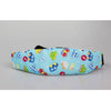 Blue fabric sleeping headrest for a baby car seat featuring colorful toys and a black strap.