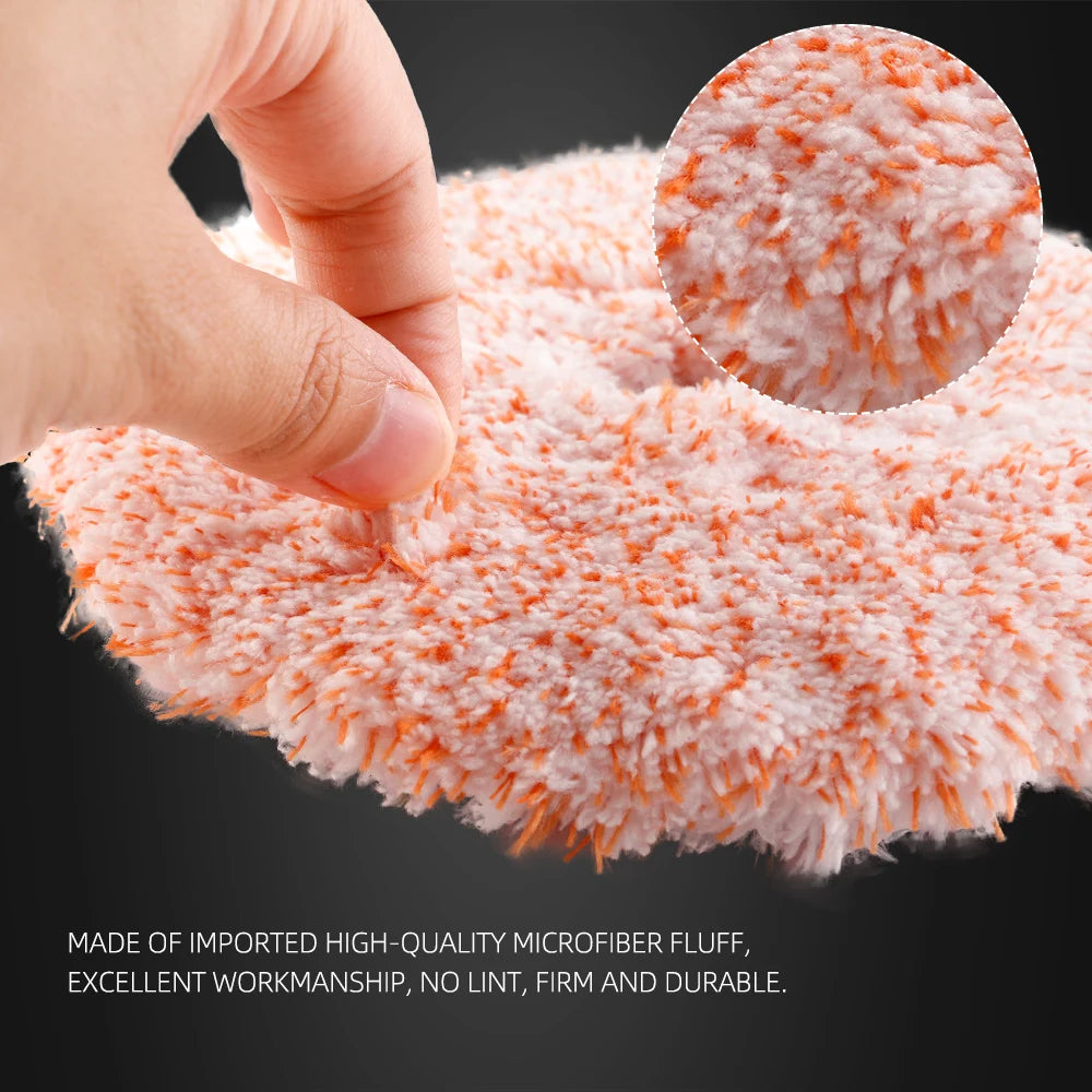 A hand is touching a bright orange microfiber fluff polishing pad used for car detailing.