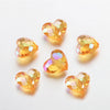 A collection of twenty clear yellow-orange acrylic heart beads for jewelry making displayed on a white surface.