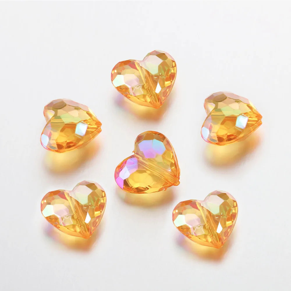 A collection of twenty clear yellow-orange acrylic heart beads for jewelry making displayed on a white surface.
