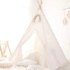 A white kids fold-able play tent with sheer curtains and decorative tassels set up indoors.