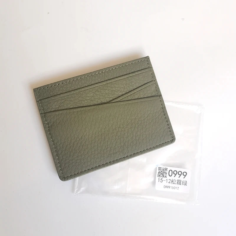 A slim, olive green genuine leather card holder wallet is shown inside a clear plastic sleeve.