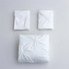 Three white queen comfort bedding items including two pillowcases and one comforter laid out on a light gray surface