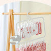 A hand is hanging pink and white laundry clips on a wooden clothes rack.