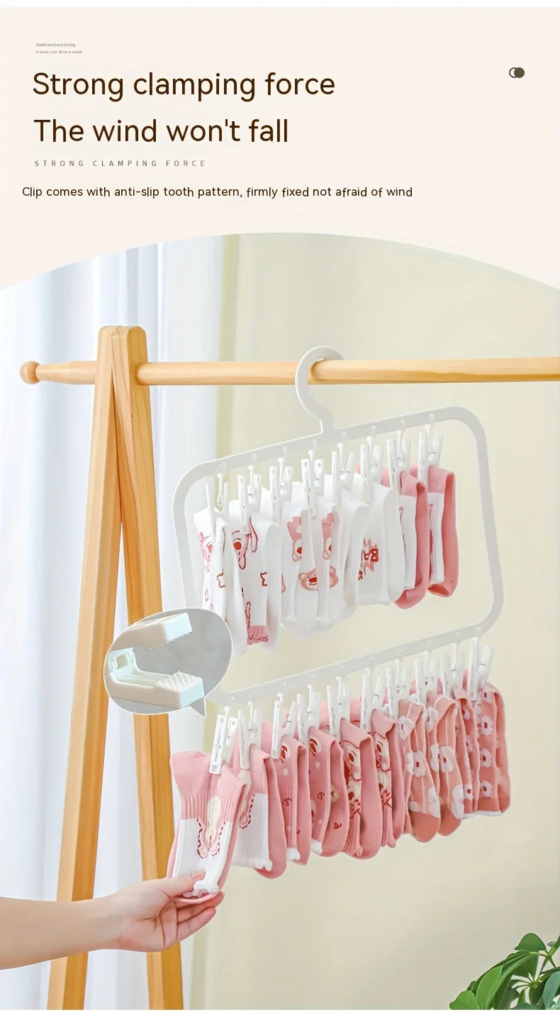 A hand is hanging pink and white laundry clips on a wooden clothes rack.