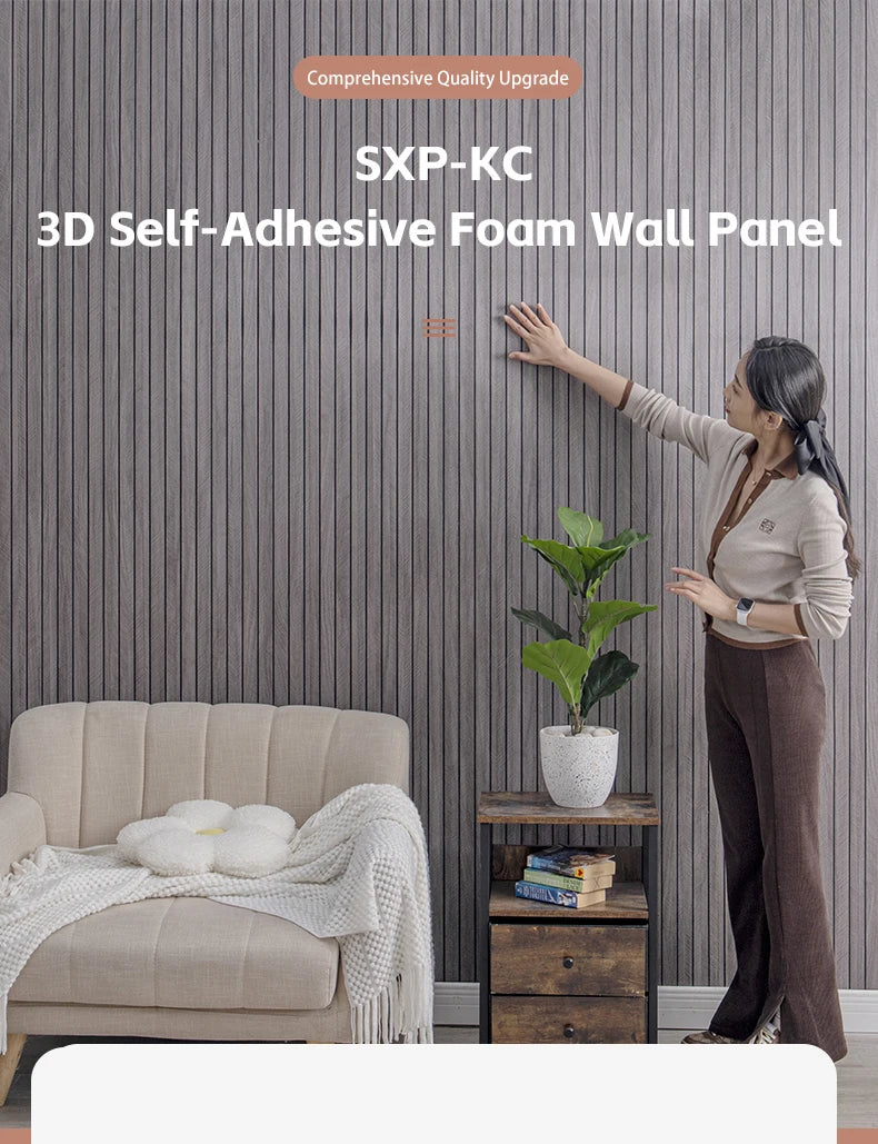 A woman is applying a 3D self-adhesive foam wall panel to a gray textured wall in a living room setting.