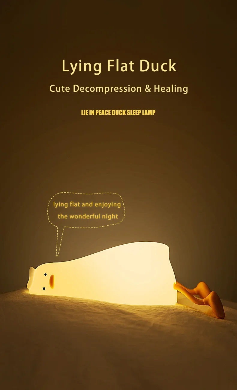 A white silicone duck night light is lying on a bed, illuminating the surrounding area.