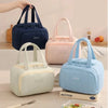 Three pastel-colored insulated quilted lunch tote bags in blue, pink, and mint green are displayed on a light wooden surface.