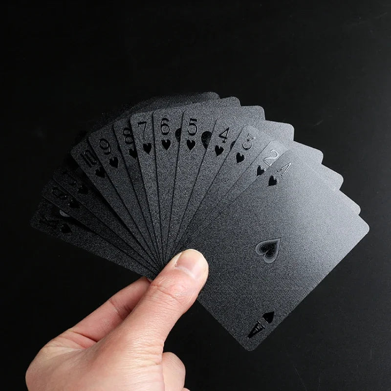 A hand holds a fan of black playing cards, showing the numbered cards from 2 to 10.