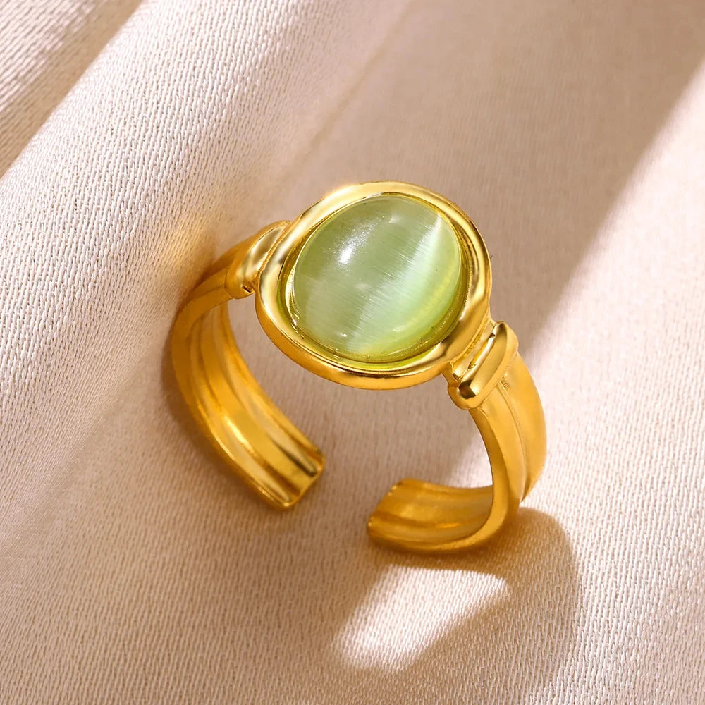 A vintage oval opal ring featuring a light green gemstone set in an adjustable gold band, resting on a beige fabric.