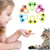 A child's finger is interacting with a set of colorful eye-shaped finger puppet rings for a party favor.