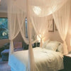 Elegant white lace canopy mosquito net draped over a bed in a bedroom setting.