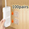 A hand is installing transparent double-sided adhesive wall hooks onto a wooden surface, demonstrating 100 pairs of storage h
