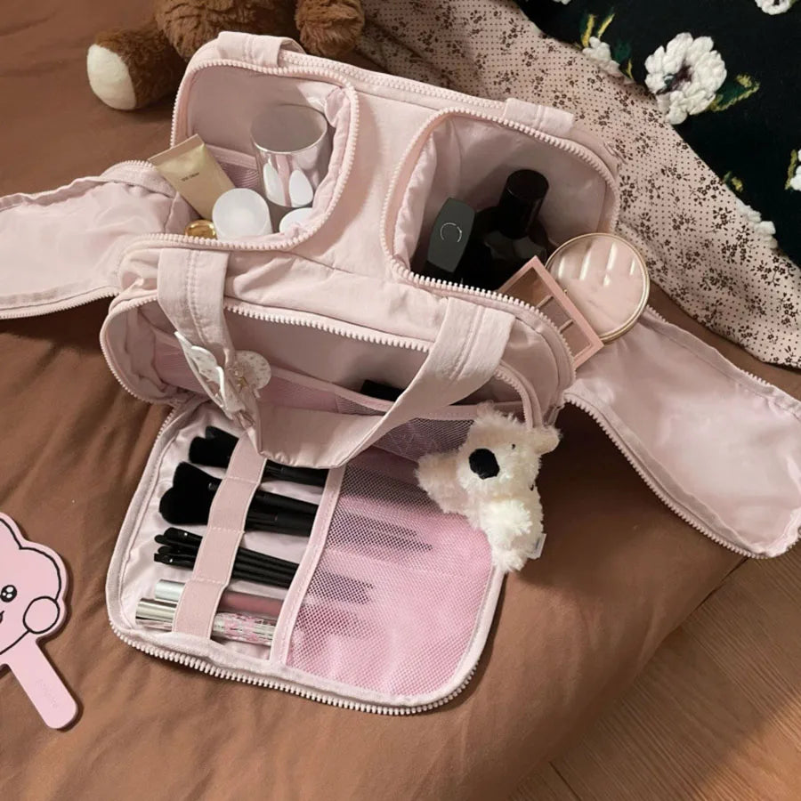 A pink cosmetic travel organizer with multiple compartments and a small white stuffed animal.