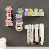 A display of various colorful, no-drill self-adhesive toilet paper holders mounted on a gray wall.