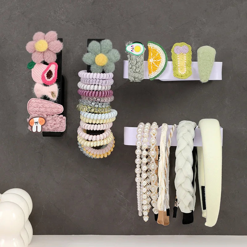 A display of various colorful, no-drill self-adhesive toilet paper holders mounted on a gray wall.