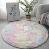 A fluffy pink and white shaggy circle area rug placed on a light gray floor.