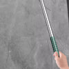 A hand is holding a long, silver silicone scraper broom and squeegee against a gray stone surface.