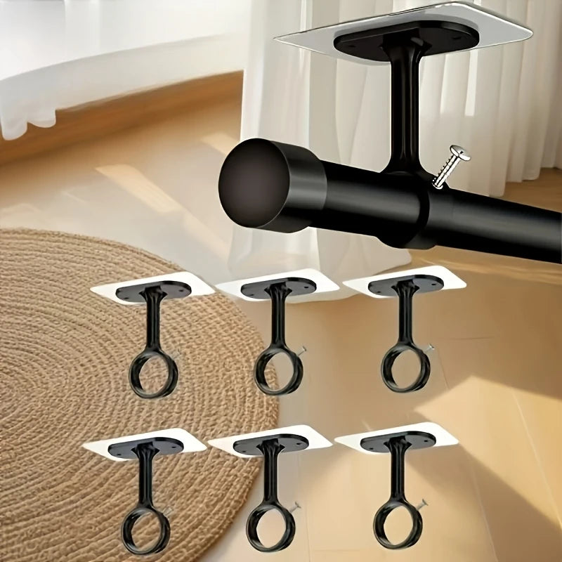 A close-up view of black self-adhesive ceiling curtain rod brackets mounted on a light-colored wall.