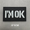 Black embroidered patch with white text I'M OK on a gray background