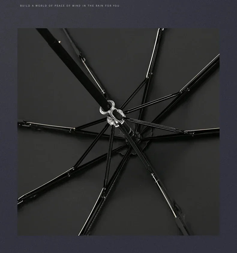 A black folding parasol or umbrella with a silver decorative element, shown from above.