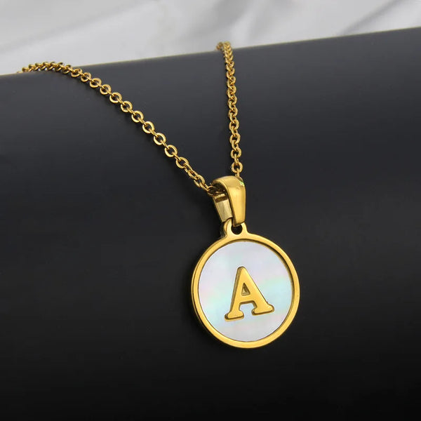 A gold-plated initial pendant necklace featuring the letter A on a white circular charm.