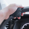 A hand grips a black steering wheel knob designed for one-hand control.