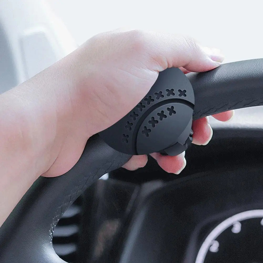 A hand grips a black steering wheel knob designed for one-hand control.