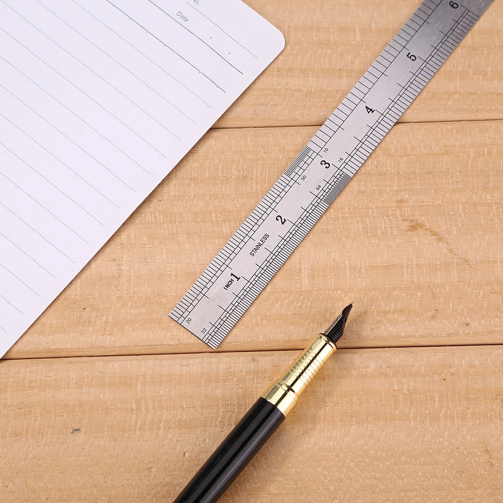 A stainless steel precision ruler is shown next to a piece of paper on a wooden surface.