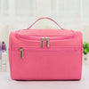 A bright pink hanging makeup bag with silver zippers is displayed on a white surface.