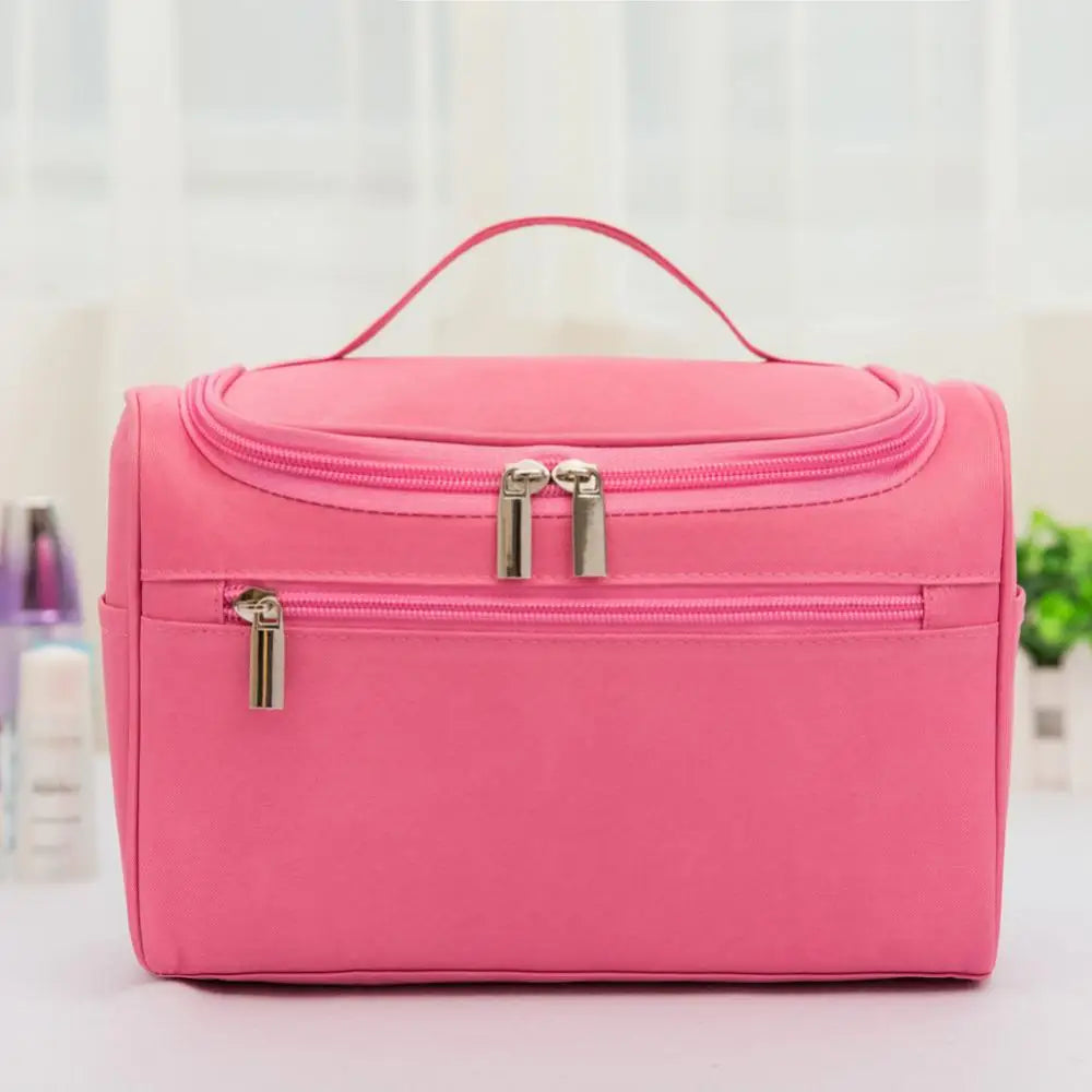 A bright pink hanging makeup bag with silver zippers is displayed on a white surface.