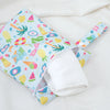 A colorful mini waterproof wet dry bag for baby with various fruit and nature patterns, shown open on a white cloth.