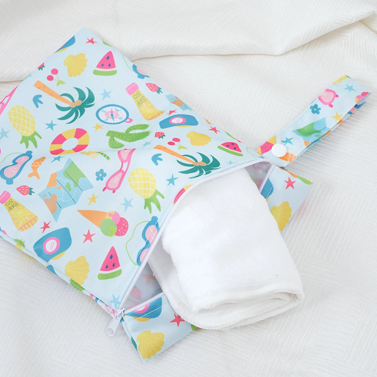 A colorful mini waterproof wet dry bag for baby with various fruit and nature patterns, shown open on a white cloth.