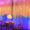 A soft pink and purple draped background with fairy lights illuminating a table and chairs.