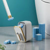 A white disposable toilet cleaning brush holder with blue replacement heads on a gray surface.