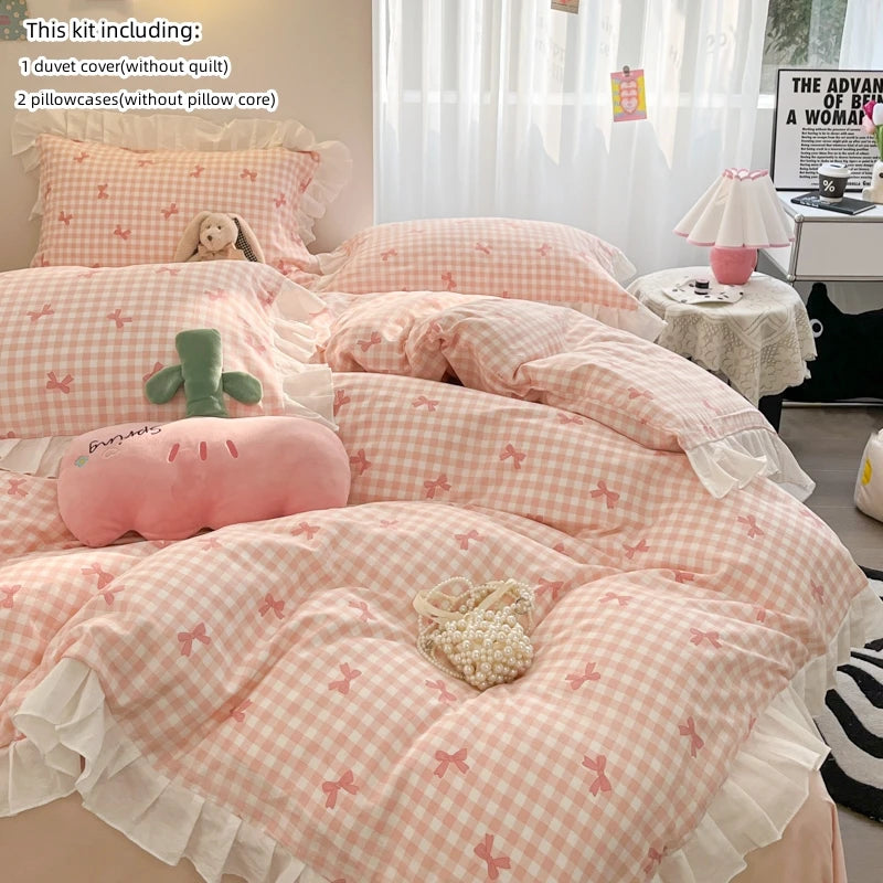 A pink and white floral patterned duvet cover set with a matching pillow and a stuffed animal on a bed.