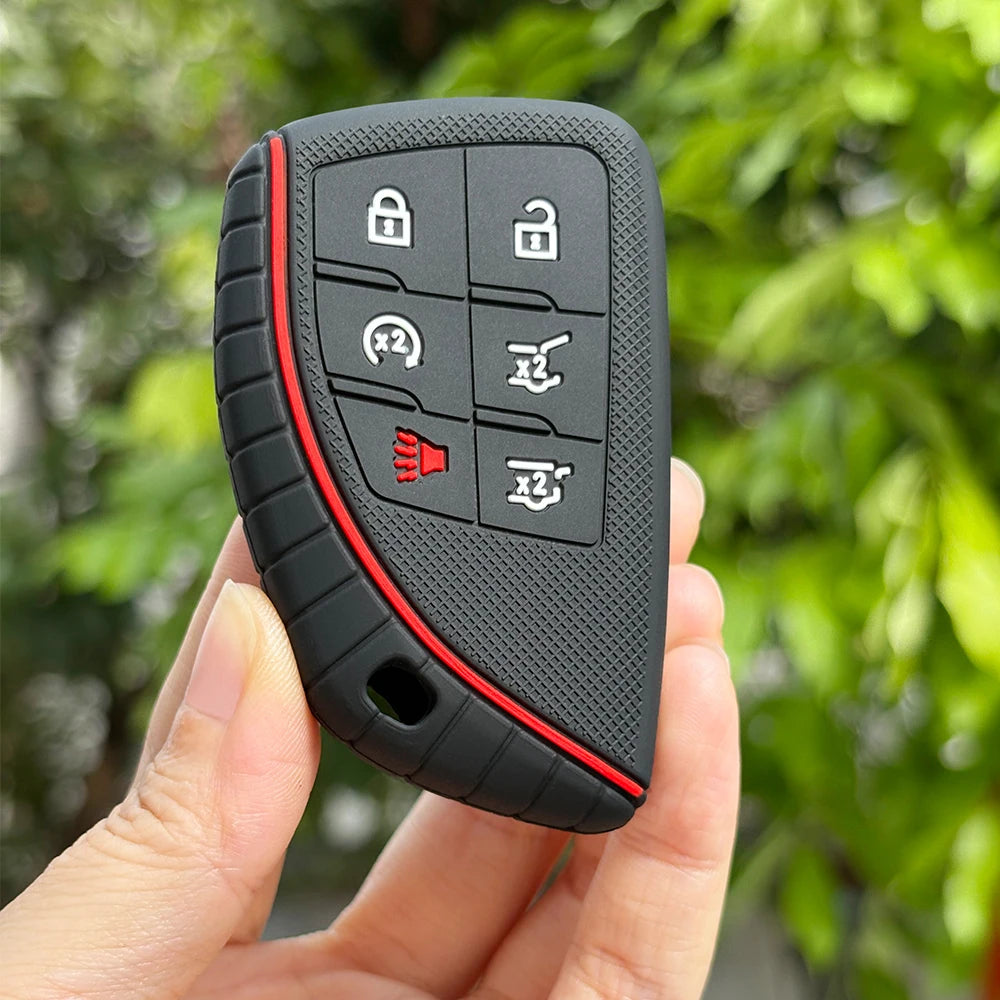 A hand holds a black silicone key fob cover with multiple buttons for Chevy, GMC, and Buick models.